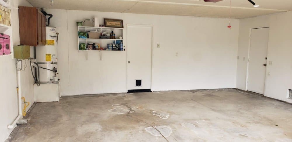 Bare stained concrete garage floor in San Diego before an epoxy coating